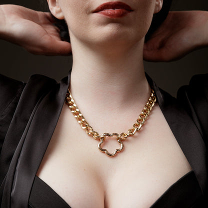 Woman wearing a gold chain bondage necklace with flower clasp a dark background