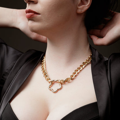 Woman wearing a gold chain necklace with a flower-shaped pendant.
